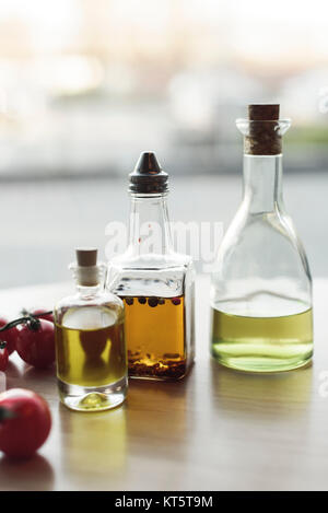 Vue rapprochée de différents types d'huile dans des bouteilles et des tomates cerises Banque D'Images