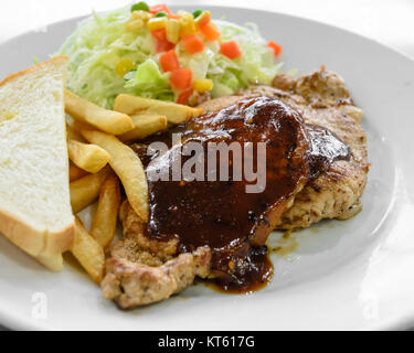 Filet de porc grillé steak avec salade et frites on white plate Banque D'Images