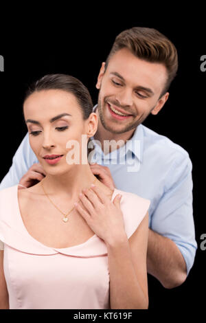 Portrait of smiling man putting on woman's bijoux cou sur noir, la Journée internationale des femmes concept Banque D'Images