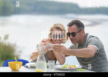 Couple heureux en tenant à selfies outdoor restaurant Banque D'Images