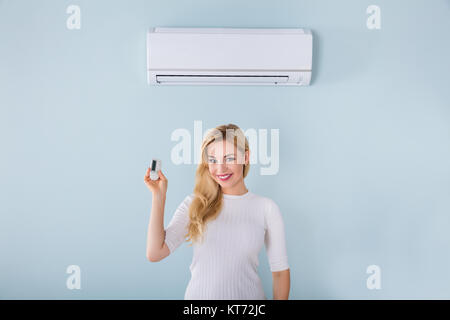 Woman Holding Remote Controller de climatiseur Banque D'Images