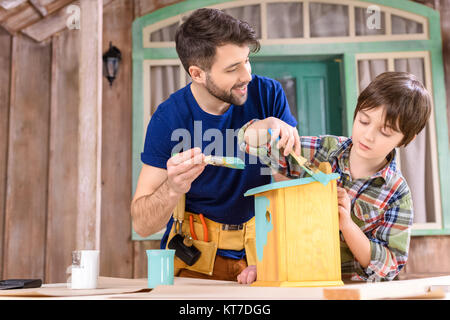 Heureux père et fils peinture petit wooden birdhouse on porch Banque D'Images