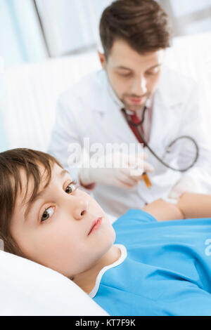 Sick boy lying on lit d'hôpital tandis que l'homme médecin making injection Banque D'Images