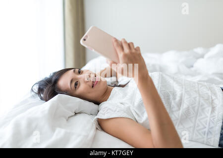 Woman using cellphone et fixer sur le lit Banque D'Images