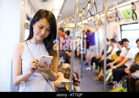 Woman using cellphone à l'intérieur du compartiment de train Banque D'Images