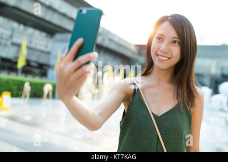 Prendre femme par selfies téléphone mobile à street Banque D'Images