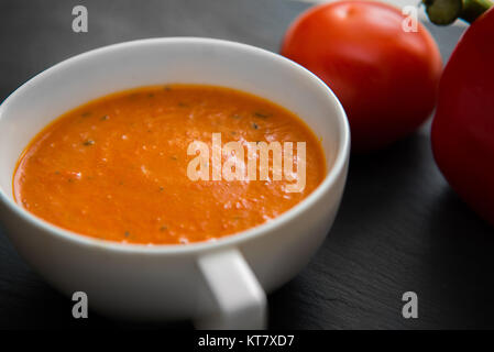 Soupe de crème aux poivrons et tomates sur la plaque noire Banque D'Images