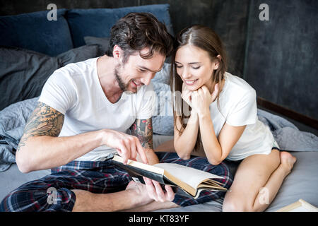 Couple reading book in bedroom Banque D'Images