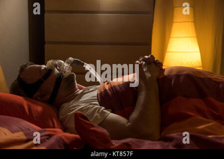 Un homme avec l'apnée du sommeil, porte un masque CPAP pendant le sommeil, masque respiratoire qui appuie sur l'air dans les voies respiratoires par surpression, prévenir les voies respiratoires Banque D'Images