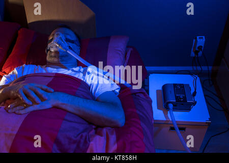 Un homme avec l'apnée du sommeil, porte un masque CPAP pendant le sommeil, masque respiratoire qui appuie sur l'air dans les voies respiratoires par surpression, prévenir les voies respiratoires Banque D'Images