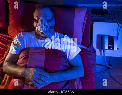 Un homme avec l'apnée du sommeil, porte un masque CPAP pendant le sommeil, masque respiratoire qui appuie sur l'air dans les voies respiratoires par surpression, prévenir les voies respiratoires Banque D'Images