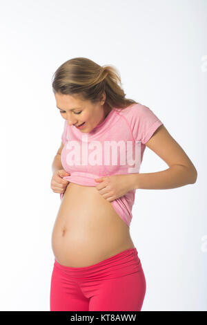 Happy pregnant woman looking at sa bosse sur un fond blanc. Banque D'Images