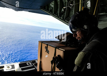 Tech. Le Sgt. Napoléon Ortiz, un C-130J Super Hercules avec le 36ème instructeur loadmaster Escadron de transport aérien, attend que le signal pour pousser un paquet à partir de la rampe de chargement d'un C-130J Super Hercules au cours de l'Opération Goutte de Noël, le 11 décembre 2017, sur l'île de SIFA. Drop est un Noël Pacific Air Forces canadiennes exercice qui comprend un partenariat entre la 374e Escadre de transport aérien, Yokota Air Base, Japon ; la 36e Escadre, Andersen Air Force Base, Guam, le 734e Escadron de la mobilité aérienne, Andersen AFB du 515e aile des opérations de mobilité aérienne, Joint Base Harbor-Hickam Pearl, Washington, l'Université de Guam ; et Banque D'Images