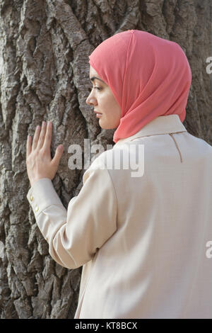 Femme musulmane portant le hijab part de toucher à l'arbre à l'écart Banque D'Images