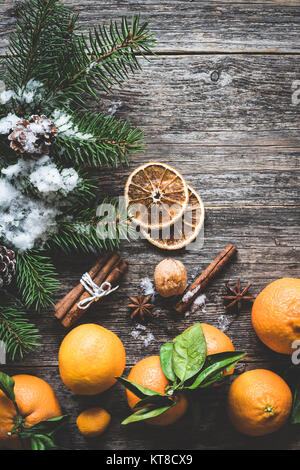 Clémentines, sapin, les épices et la neige sur le vieux fond de bois. Composition d'hiver noël Banque D'Images