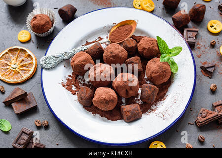 Truffes au chocolat noir maison sur plaque blanche décorée de feuilles de menthe. Composition horizontale Banque D'Images