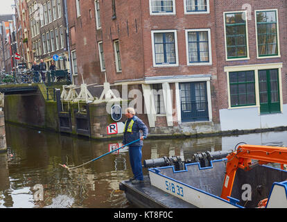 Homme debout sur le nettoyage de la litière de pêche Barge Canal, Amsterdam, Holland Banque D'Images