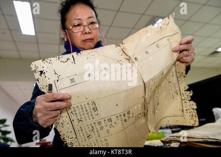 (171222) -- Chengdu, 22 déc., 2017 (Xinhua) -- Dongjue Yuan divise l'un bloque la page d'un livre plus de 180 ans, dans la bibliothèque provinciale du Sichuan dans le sud-ouest de Chengdu, capitale de la province chinoise du Sichuan, le 21 décembre 2017. Un Dongjue Yuan, 70 ans, expert de vieux livres de réparations, a continué de travailler sur la réparation et la conservation de livres anciens depuis 1983 en centre de réparation des livres anciens de la bibliothèque provinciale du Sichuan. Dans sa carrière de 34 ans de temps, Yuan a réparé environ 200 livres chinois antiques précieux, certains d'entre eux pourraient remontent à 1 000 ans. Les travaux de réparation se compose de plus de 10 étapes différentes. À r Banque D'Images