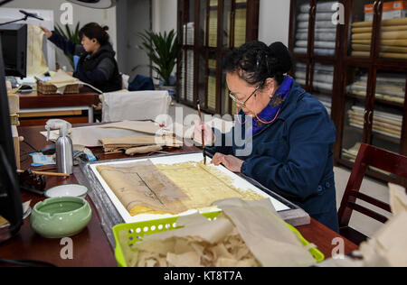 (171222) -- Chengdu, 22 déc., 2017 (Xinhua) -- Dongjue Yuan un réparations page d'un livre plus de 180 ans, dans la bibliothèque provinciale du Sichuan dans le sud-ouest de Chengdu, capitale de la province chinoise du Sichuan, 21 Décembre, 2017. Un Dongjue Yuan, 70 ans, expert de vieux livres de réparations, a continué de travailler sur la réparation et la conservation de livres anciens depuis 1983 en centre de réparation des livres anciens de la bibliothèque provinciale du Sichuan. Dans sa carrière de 34 ans de temps, Yuan a réparé environ 200 livres chinois antiques précieux, certains d'entre eux pourraient remontent à 1 000 ans. Les travaux de réparation se compose de plus de 10 étapes différentes. Pour réparer Banque D'Images