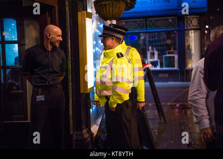 Pays de Galles Aberystwyth UK, vendredi 22 décembre 2017 Les gens dehors sur la ville d'Aberystwyth, Pays de Galles, le Mad vendredi ou Booze Vendredi noir, le dernier vendredi soir avant le jour de Noël, où traditionnellement les travailleurs de l'UK sortira pour fêter le début de leurs vacances de Noël avec leurs collègues, en sachant qu'ils ont tout le week-end pour récupérer. Sur la photo : deux policiers vérifier avec la porte de la sécurité sur un centre-ville pub Crédit photo : Keith Morris/Alamy Live News Banque D'Images