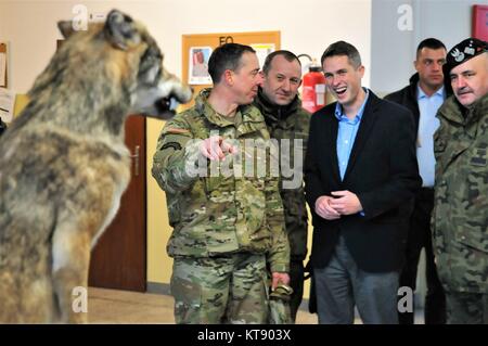 Le Lieutenant-colonel de l'armée américaine Scott Cheney, commandant du Groupement tactique de la Pologne, à gauche, explique l'histoire du régiment meute de mascotte à ministre de la Défense britannique Gavin Williamson, centre, au cours d'une visite à l'OTAN de troupes de combat Group Pologne 22 décembre 2017 dans Bemowo Piskie, Pologne. Banque D'Images