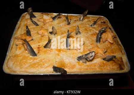 Mousehole, Cornwall, UK. 26Th Dec 2017. Tom Bawcocks Eve. Le légendaire Tom Bawcock sauvé le village de Mousehole de famine en allant à la pêche dans une violente tempête. Pendant le festival une Stargazy pie est faite d'un mélange du poisson, des oeufs et de pommes de terre avec des têtes de poissons et de la queue qui dépasse de la tarte. La tarte est habituellement servi gratuitement dans l'auberge de bateau local. Crédit : Simon Maycock/Alamy Live News Banque D'Images