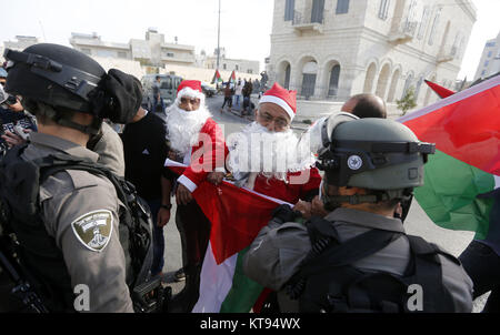 Bethléem, Cisjordanie, territoire palestinien. 26Th Dec 2017. Palestiniens déguisés en père Noël, faire face à la police des frontières israélienne au cours d'une manifestation dans la ville cisjordanienne de Bethléem, Samedi, Décembre 23, 2017. protester contre le président américain Donald Trump' ?s'annonce de reconnaître Jérusalem comme capitale d'Israël et d'un déménagement de l'ambassade américaine de Tel Aviv à Jérusalem : Crédit Hashlamoun Wisam APA/Images/ZUMA/Alamy Fil Live News Banque D'Images