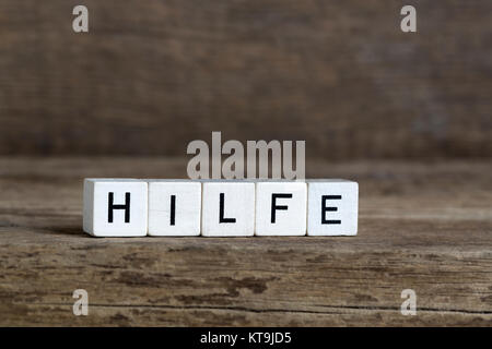 Mot allemand aide, écrit en cubes on a wooden background Banque D'Images