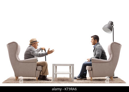 Un homme âgé et un jeune mec assis dans des fauteuils et avoir une conversation isolé sur fond blanc Banque D'Images