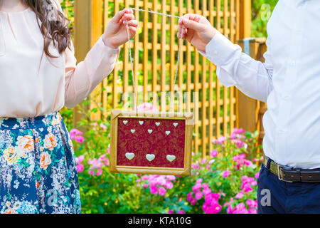 Couple holding wooden frame in hands Banque D'Images