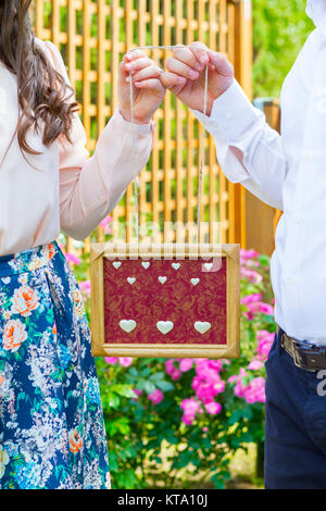 Couple holding wooden frame in hands Banque D'Images