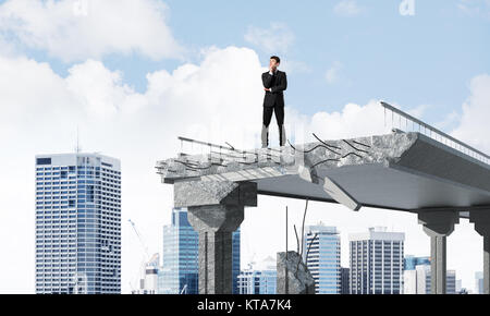 Confident businessman in suit à l'écart en se tenant sur le pont cassé avec cityscape sur arrière-plan. Le rendu 3D. Banque D'Images