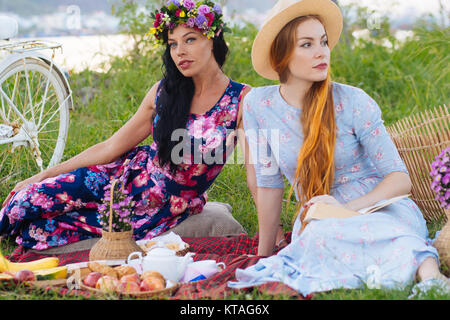 Deux belles jeunes filles en longues robes on picnic Banque D'Images