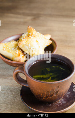 Du thé vert et de pâtés sur table en bois rustique Banque D'Images