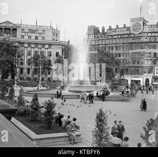 Le noir et blanc vue de Trafalgar Square à Londres, prise vers 1950, montrant une fontaine et des groupes de personnes. Banque D'Images