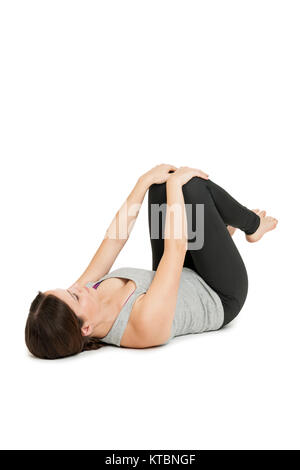 Flachwinkelige Ganzkörper-Ansicht und auf dem Rücken liegenden jungen Frau in der glückliches Yogaposition 'Baby' (anada balasana) auf weißem Hintergrund. Banque D'Images