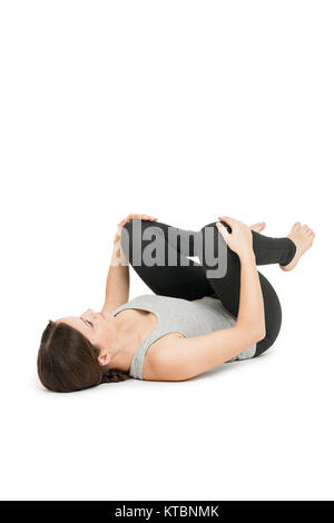 Flachwinkelige Ganzkörper-Ansicht und auf dem Rücken liegenden jungen Frau in der glückliches Yogaposition 'Baby' (anada balasana) auf weißem Hintergrund. Banque D'Images