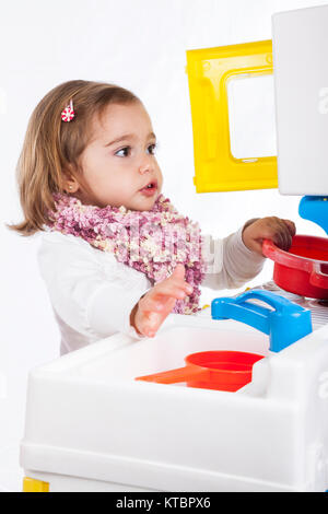 Petite fille blonde jouant avec son jouet cuisine Banque D'Images