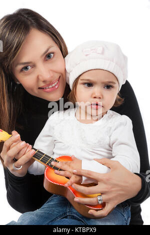 Petite fille et sa maman jouer avec une guitare jouet Banque D'Images