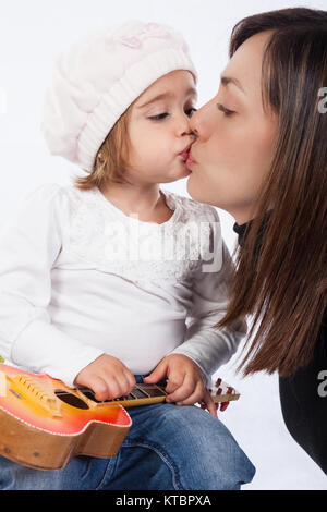 Petite fille et sa maman jouer avec une guitare jouet Banque D'Images