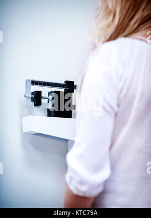 Photo d'une femme à l'arrière debout sur la balance de la clinique et de contrôler son poids, mode de vie sain, les régimes et la perte de poids concept Banque D'Images