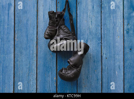 Gants de boxe vintage noir accroché sur un vieux clou rouillé Banque D'Images