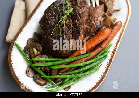 De mijotés avec les haricots verts, les carottes et les champignons sur une assiette blanche. Nappe grise, garnir de thym. Copier l'espace. Banque D'Images