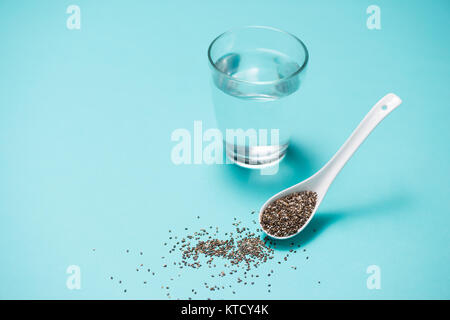 Verre d'eau et des graines de chia dans une cuillère. L'espace du texte. Banque D'Images