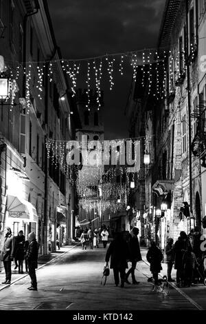 Vue de la rue principale à Assise (Ombrie) pendant la période de Noël, avec les gens à faire leurs achats, décorations de lumière et le clocher de la Piazza del Comune Banque D'Images