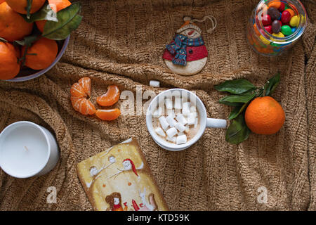 Une tasse de Cappuccino aromatique avec de la guimauve, mandarines mûres, une bougie, une décoration d'un arbre de Noël sous la forme d'un bonhomme et un pot. Banque D'Images