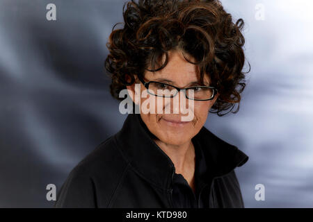Femme d'âge moyen avec des cheveux bruns frisés noir portant des lunettes de lecture et souriant Banque D'Images