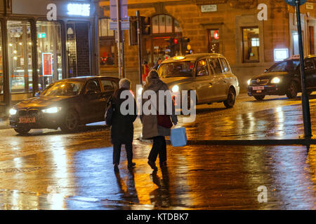 La nuit urbaine graveleuse humide Glasgow street life femmes mère et fille de retour à la maison en marchant sur les sacs de la rue d'un voyage d'achats taxi tard dans la nuit Banque D'Images