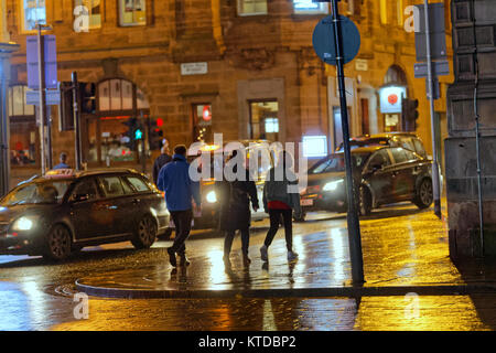 La nuit urbaine graveleuse humide Glasgow street life trois jeunes hommes marchant sur la rue entre les barres ensemble tard dans la nuit Banque D'Images