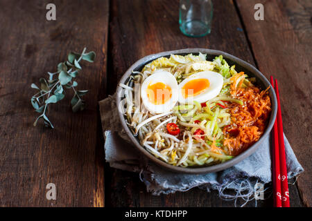 Bol de soupe de nouilles Udon sans gluten avec des carottes, chou chinois, germes de haricots mungo, zoodles et oeuf dur Banque D'Images